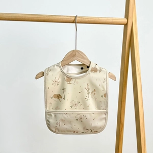 Waterproof baby bib detail with hedgehog and mushroom prints and a crumb catcher pocket