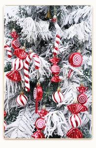 Red and white Christmas candy ornaments with spiral patterns on a snowy tree branch