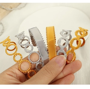 Detail of stacked vintage Cuban chain bracelets and open C-shape gold silver bangles