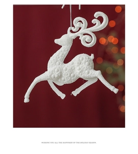 Macro view of white glitter reindeer ornament with textured finish on a festive red background