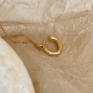 Detailed close-up of golden horseshoe pendant necklace on textured cream background