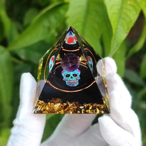 Macro shot of resin crystal pyramid with purple sphere, skull and gold metal flakes