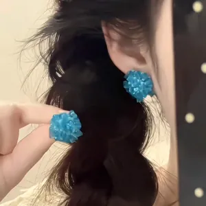 Detail of bright blue flower cluster earrings with textured resin petals on a model
