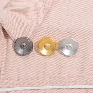 Macro shot of gunmetal gold and silver metal buttons with crown crest on pink fabric