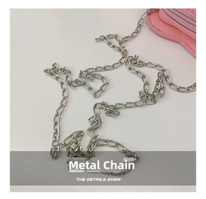 Detail view of the silver metal chain strap and stitching on the pink girl shoulder bag
