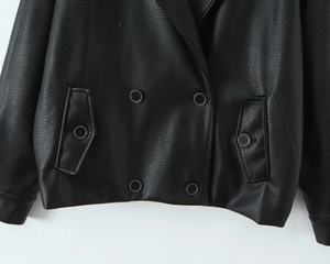 Detail of black faux leather jacket with double-breasted buttons and side pocket texture