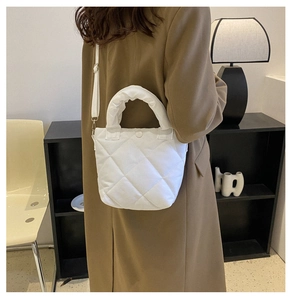 Detailed view of white quilted puffer bucket bag featuring soft rhomboid texture and handle