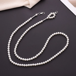 Detail of white handmade pearl phone strap with silver metal lobster clasps on black surface