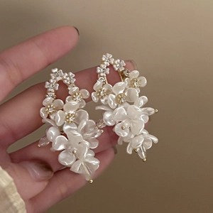 Macro shot of shell flower earrings with shimmering zircons and gold petal accents