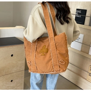 Detail of vintage brown canvas tote bag featuring frayed edges and wide shoulder strap