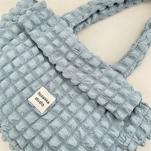 Detail of light blue bubble textured canvas bag featuring minimalist white fabric brand label