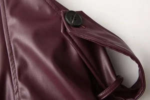 Detail of burgundy PU leather jacket featuring black round buttons and precise stitching