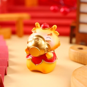 Detail of a resin dragon figurine holding a gold ingot with festive Chinese luck symbols
