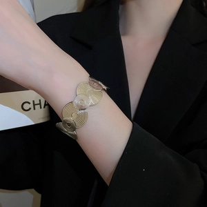 Detail of wide open cuff bracelet with concentric circles texture on black blazer