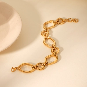 Detail of gold irregular geometric link bracelet with lobster clasp on beige background
