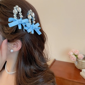 Détail d'un nœud papillon en satin bleu clair avec strass sur cheveux bouclés
