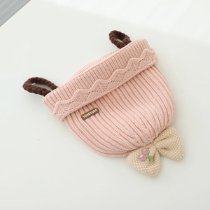 Détail du bonnet tricoté pour bébé avec nœud crème, broderie cerise et maille côtelée douce