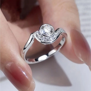 Anillo de plata con piedra redonda y detalles de diamantes ondulados en la mano