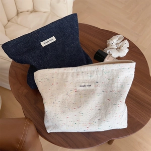 Close-up of denim and beige canvas makeup bags with minimalist Simple Wish labels