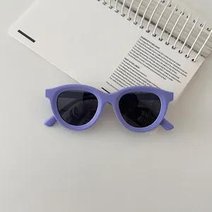 Detail of purple soft silicone kids sunglasses with dark polarized lenses on a notebook