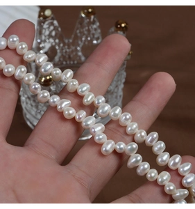 Macro shot of 4-5mm irregular natural freshwater pearls strands held in hand with soft luster