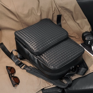 Detail of black woven leather backpack styled with headphones and sunglasses on a jacket