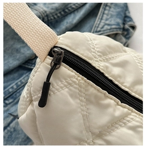 Détail de la fermeture éclair noire et du motif matelassé sur le sac crème chic