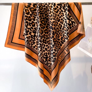 Detail of leopard print silk scarf with orange-brown pattern and black hemmed edges