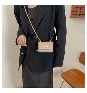 Close-up of a beige quilted mini chain bag worn as a crossbody with a gold twist-lock