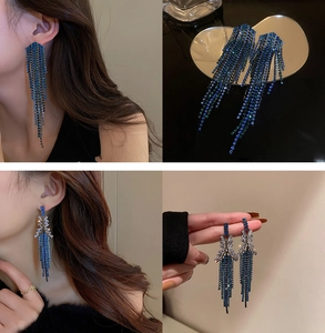 Detailed view of silver U-shaped earrings with sparkling blue tassels and rhinestones
