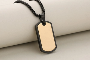 Macro shot of gold and black stainless steel dog tag pendant with elegant box chain