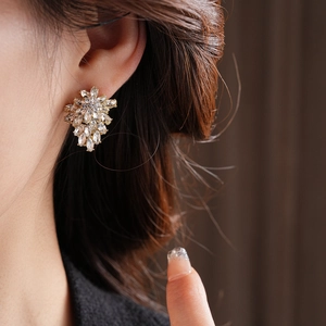 Detailed close-up of gold leaf cluster earrings with sparkling zircon crystals on model