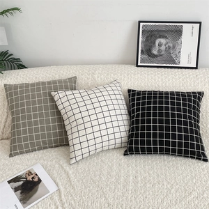 Detail of plaid cotton linen pillow covers in green and black on a soft white sofa