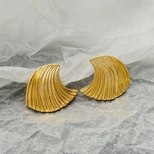 Macro detail of gold-plated starfish shell earrings with textured relief on stone background