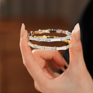 Detail of gold and silver bamboo-style bangles with mother-of-pearl inlays on a model