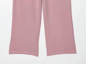 Détail de la texture en maille côtelée rose et de l'ourlet du pantalon en velours