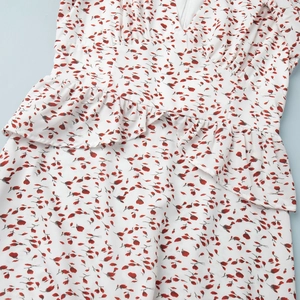 Détail de robe à col en V avec taille à basque volantée et imprimé floral rouge délicat