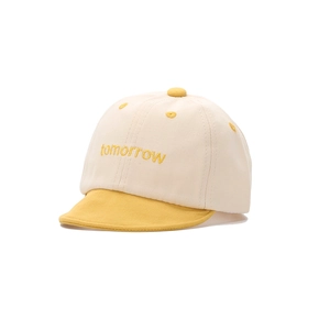 Détail d'une casquette bébé avec broderie jaune tomorrow sur tissu en coton crème