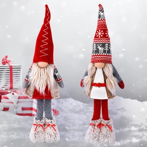 Standing Christmas gnomes plush dolls in red and grey knit fabric on outdoor snow background