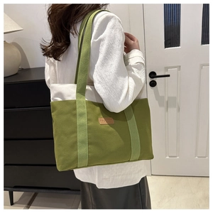 Detail of green and white canvas tote bag with leather tag and spacious shoulder strap