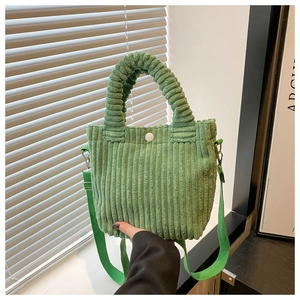 Detailed view of green corduroy bucket bag with textured handle and fabric shoulder strap