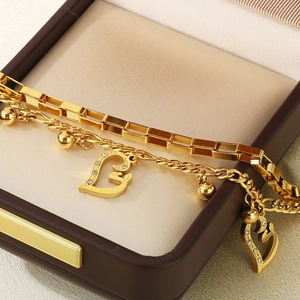 Detail of layered gold stainless steel bracelets with heart zircon charm in a gift box