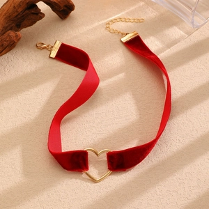Dettaglio choker in velluto rosso con fibbia a cuore dorata e chiusura regolabile