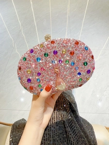 Close-up of pink crystal evening bag with intricate peacock pattern and colorful gems