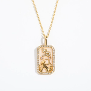 Detailed macro view of gold Capricorn pendant with crystals and pink glaze finish
