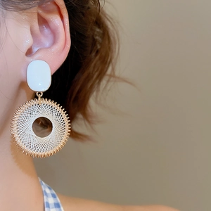 Macro detail of French style dreamcatcher hoop earrings with woven texture on model