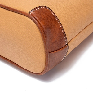 Detailed close-up of tan lychee leather stitching and vintage brown trim texture