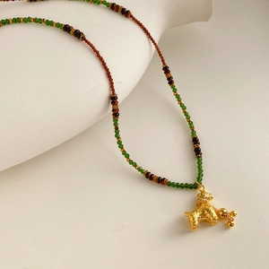 Close-up of vintage beaded necklace with brown tiger eye beads and golden pony pendant