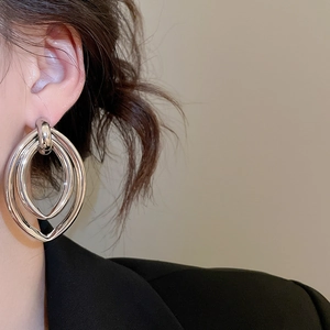 Détail de boucles d'oreilles ovales argentées multicouches avec finition miroir poli