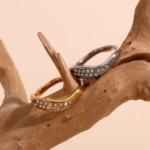 Detailed view of wave-shaped rings with sparkling zircons on a wooden branch